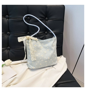 Detailed view of daisy print plaid handbag with a decorative cream lace bow detail