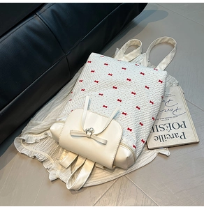 Detailed view of white textured backpack with red bow embroidery and pearl charm