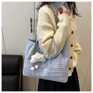 Detail of light blue tweed tote bag with woven strap and a cute white cloud pendant