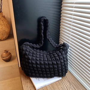 Soft black puff cloud shoulder bag with popcorn texture displayed on a wooden table