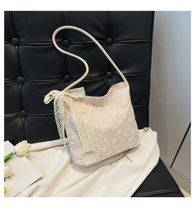 Detail of checkered canvas bag with daisy print and a large white lace bow accent