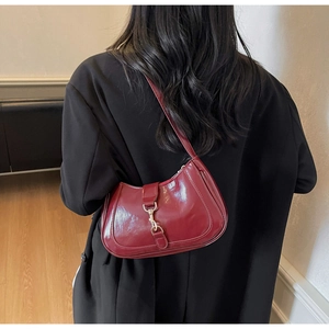 Détail du sac hobo bordeaux en cuir avec boucle dorée porté à l'épaule