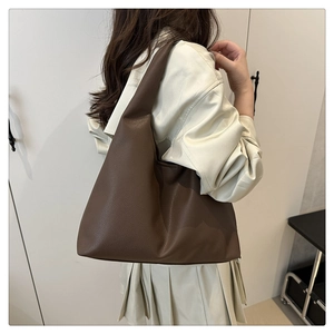 Detail of dark coffee leather hobo bag with litchi texture on model's shoulder