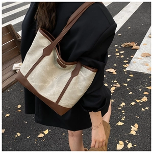Dettaglio della borsa tote vintage con finiture in pelle marrone su sfondo urbano