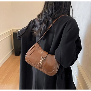 Détail d'un sac sous le bras en cuir glacé marron avec boucle élégante en métal doré