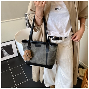 Dettaglio della borsa tote in tela opaca con toppa FASHION e ciondolo orsetto di peluche