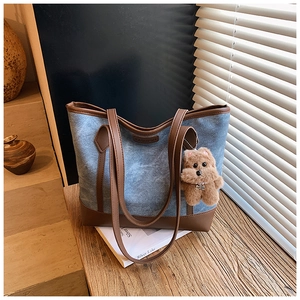Dettaglio della borsa tote in denim e pelle con ciondolo a forma di orsetto