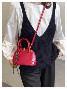 Detail of red shell handbag with glossy finish and woven decorative charm accessory