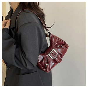 Detail of dark red glossy underarm bag with silver buckles and retro punk hardware