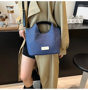 Detail der blauen Denim-Tragetasche mit schwarzen Ledergriffen und verstellbarem Riemen