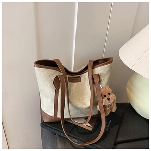 Dettaglio della borsa tote in tela con finiture in pelle marrone e ciondolo a forma di cane