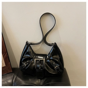 Close-up of black patent leather underarm bag with silver buckles and retro moto style