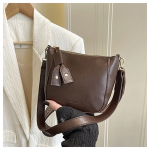 Detail der dunkelbraunen Halbmondtasche mit FASHION-Prägung und Lederfransen-Quaste