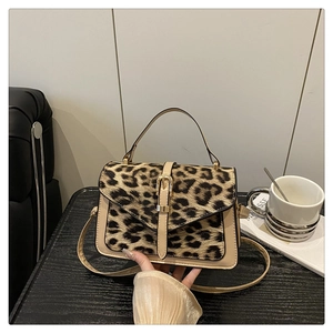 Close-up of leopard print crossbody bag with beige leather trim and golden buckle