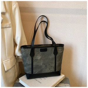 Dettaglio macro della borsa tote grigia alla moda con cinturini in pelle nera e logo FASHION