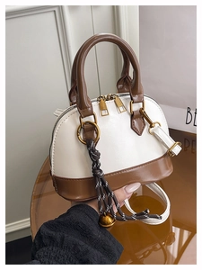 Detail of two-tone shell handbag with crocodile texture and creative bell pendant