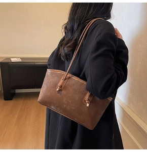 Detail of vintage brown tote bag showing knotted shoulder strap and embossed lettering