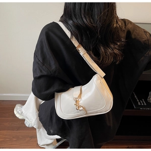 Détail du sac à bandoulière en cuir crème avec boucle dorée sur un mannequin