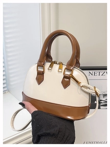 Detail view of contrast color shell bag with cream leather and brown handle grip