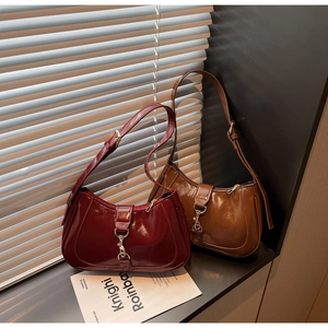 Détail de sacs hobo brillants bordeaux et havane avec boucles métalliques au soleil