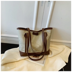 Dettaglio della borsa tote in tela con finiture in pelle marrone e tag alla moda
