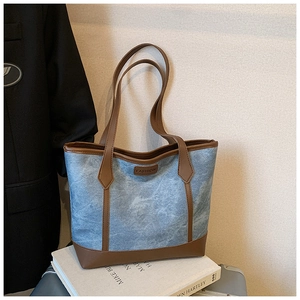 Dettagli della borsa tote in denim blu con finiture in pelle marrone e placca retrò