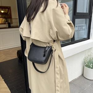 Schwarze minimalistische Leder-Umhängetasche mit breitem Gurt an Model im Outdoor-Streetstyle