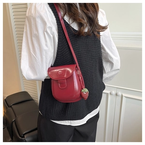 Dettaglio della mini borsa a tracolla rosso brillante con texture in pelle e ciondolo