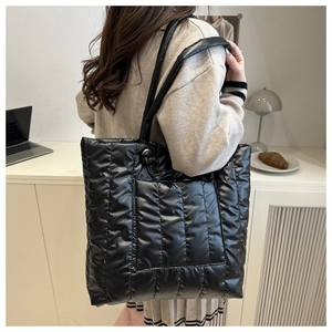 Detailed view of quilted black tote bag with shoulder strap worn in lifestyle setting