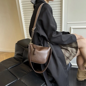 Dunkelbraune Lederumhängetasche mit Vintage-Gurt und goldenen Details am Modell