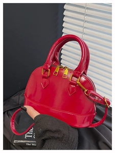 Macro view of red patent leather shell bag with gold zippers and detachable strap