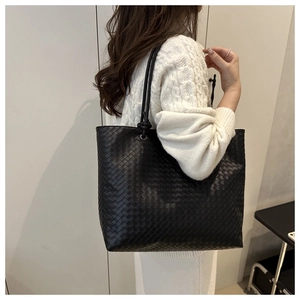 Detail of black woven leather tote bag showing the Intrecciato texture and long shoulder strap