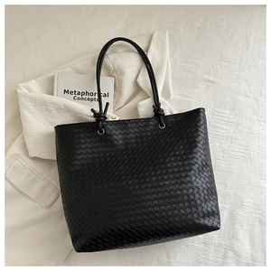 Detail of black woven leather tote bag featuring iconic knots and silver eyelets