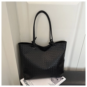 Detail of black woven leather tote bag with round handles and knotted decorative accents