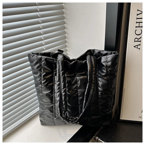 Detail of glossy black quilted tote bag showing down-padded fabric and texture