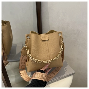 Close-up of pebble leather bucket bag featuring metal chain and jacquard woven strap