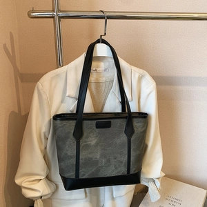 Borsa tote retrò grigia con trama marmorizzata e tracolla nera su una giacca