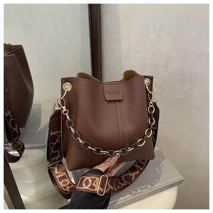 Detail view of dark brown pebbled leather bucket bag with fashion buckle and woven strap