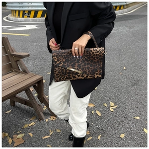 Gros plan de la pochette léopard avec bordure métallique tenue par un mannequin chic