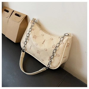 Detail der beigen Baguette-Tasche mit Cartoon-Print und Schulterriemen aus Kette