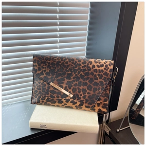 Détail d'une pochette léopard avec bordure dorée posée sur un livre au style minimaliste