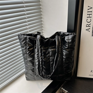 Quilted black puffer tote bag with glossy finish and spacious trapezoid design