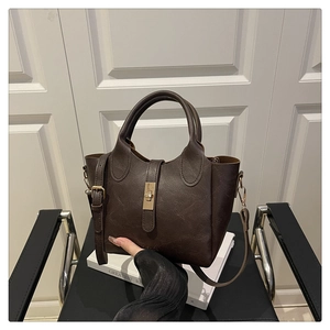 Detail of dark brown bucket bag with gold square lock and vintage leather texture