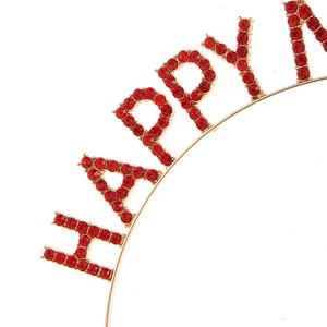 Detailed close-up of a festive gold headband featuring red rhinestone HAPPY lettering