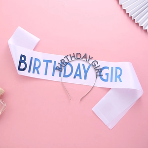 White satin BIRTHDAY GIRL sash and blue rhinestone headband set on pink background