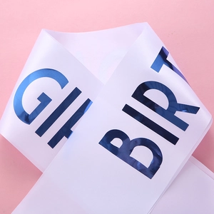Close-up of white satin birthday girl sash with metallic blue lettering on pink background