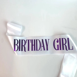 Détail de l'écharpe en satin blanc avec lettrage Birthday Girl holographique violet