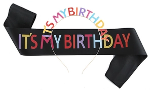 Detail of black satin birthday sash and metallic headband with colorful rainbow lettering