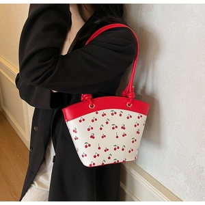 Detail of white cherry print crossbody bag with red knot shoulder strap on model