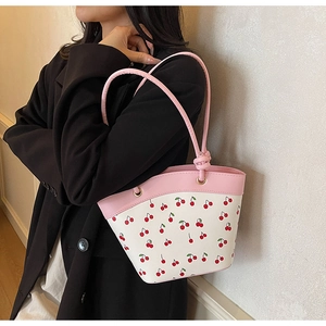 Close-up of cherry print crossbody bag with pink leather handles and gold metal rings